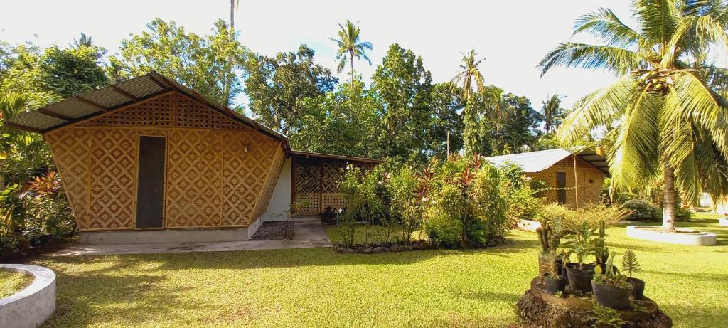une petite maison dans une cour avec des palmiers dans l'établissement Bat Tree Cottages, à Agoho