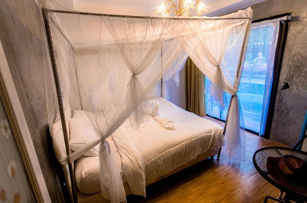 1 dormitorio con cama con dosel y cortinas blancas en บ้านสวีทคาบาน่า และบ้านสวีทโอโซนBy The mountain Ozone บ้านโอโซนขุนเขาแก่งกกระจาน en Ban Song Phi Nong