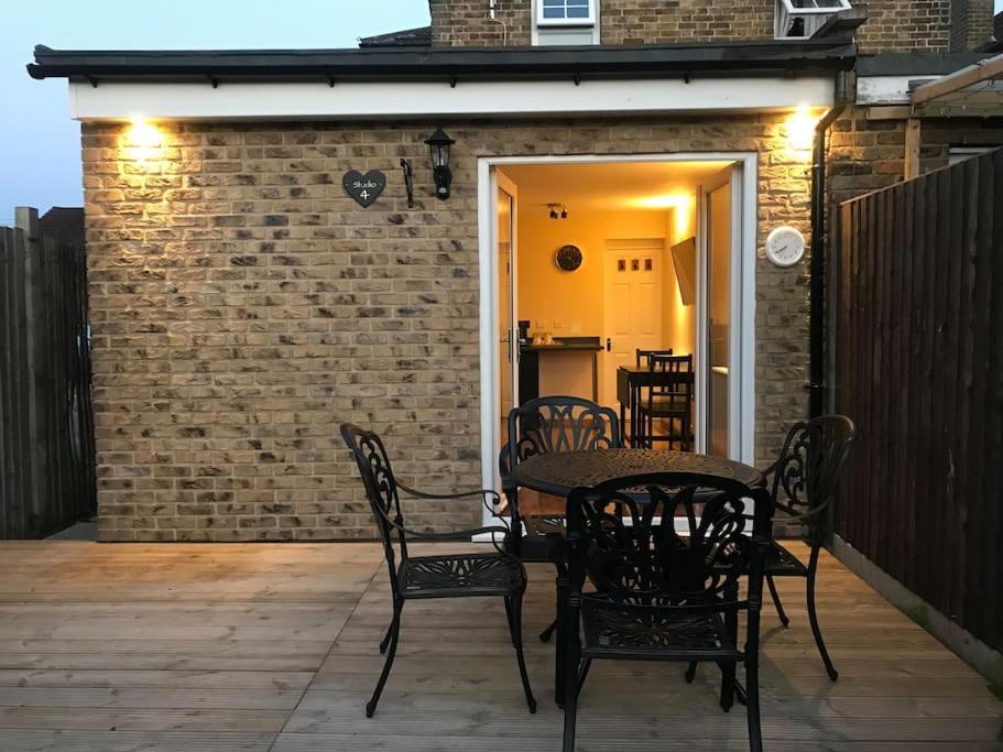 a patio with a table and chairs and a brick wall at Studio-4 for professionals in Staines