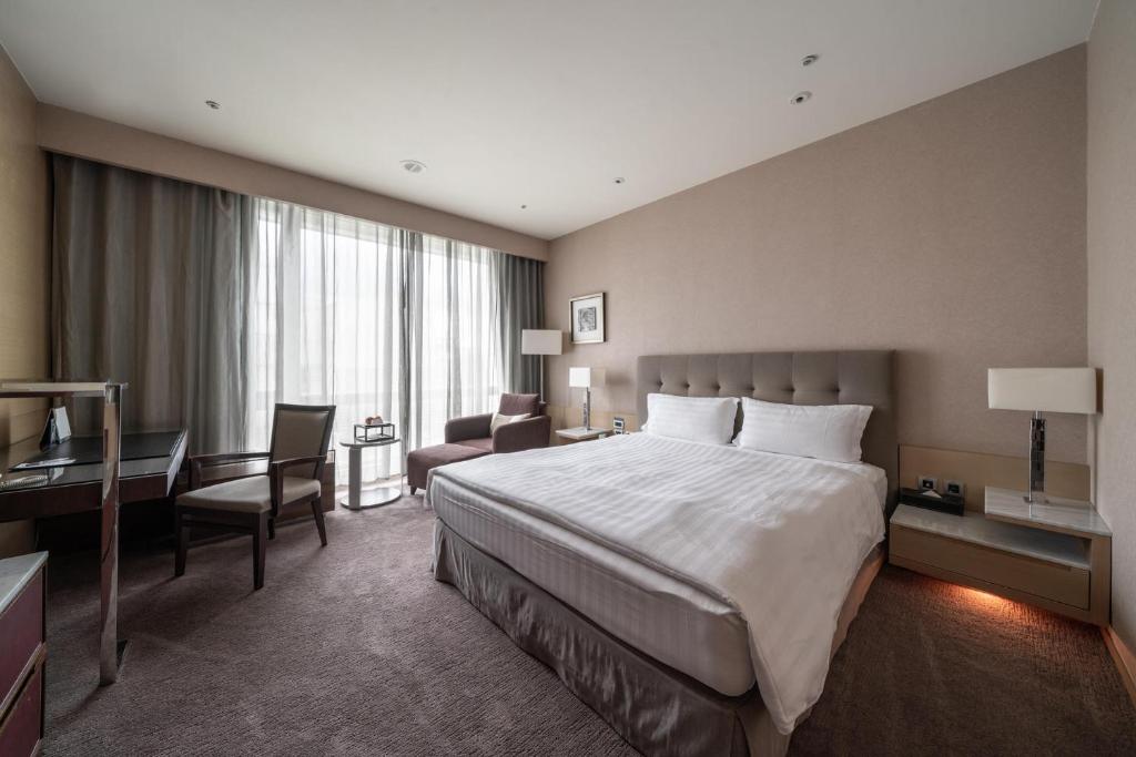 a hotel room with a large bed and a desk at Taipung Suites in Anping