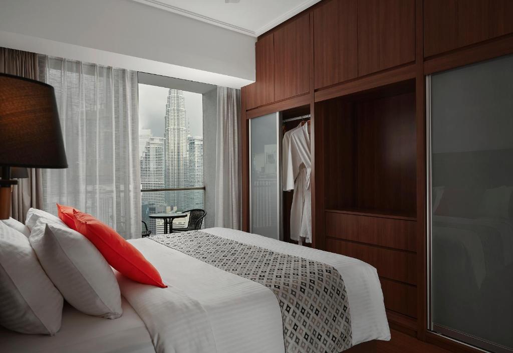 Un dormitorio con una cama con almohadas rojas y una ventana en TRILLION SUITES by SLG en Kuala Lumpur