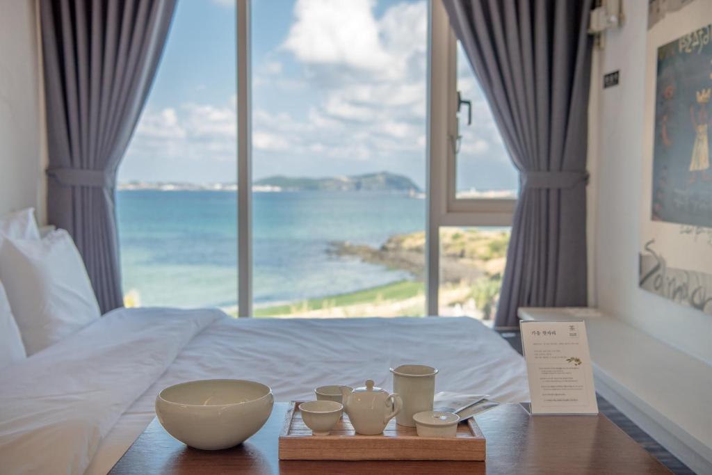 a room with a bed with a view of the ocean at Chuidasun Resort Tea & Meditation in Seogwipo