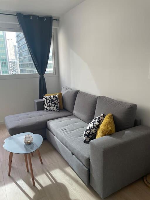 ein Wohnzimmer mit einem grauen Sofa und einem Tisch in der Unterkunft Superbe appartement au cœur de La Défense in Courbevoie