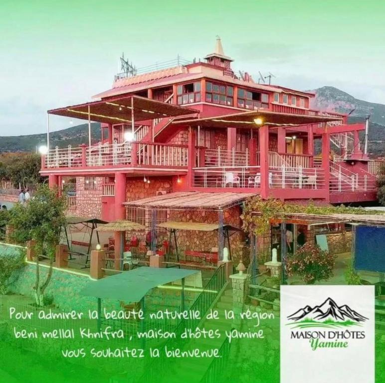 - un grand bâtiment rouge avec un panneau devant dans l'établissement maison d'hôtes yamine, à Béni Mellal