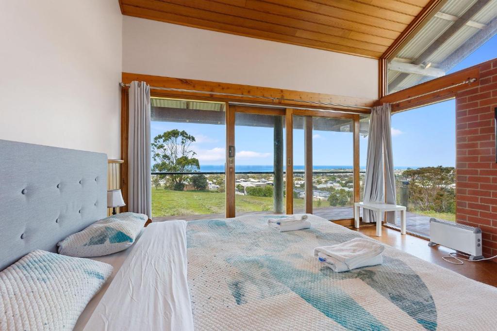 a bedroom with a large bed with a view of the ocean at Apollo Panorama Guesthouse in Apollo Bay