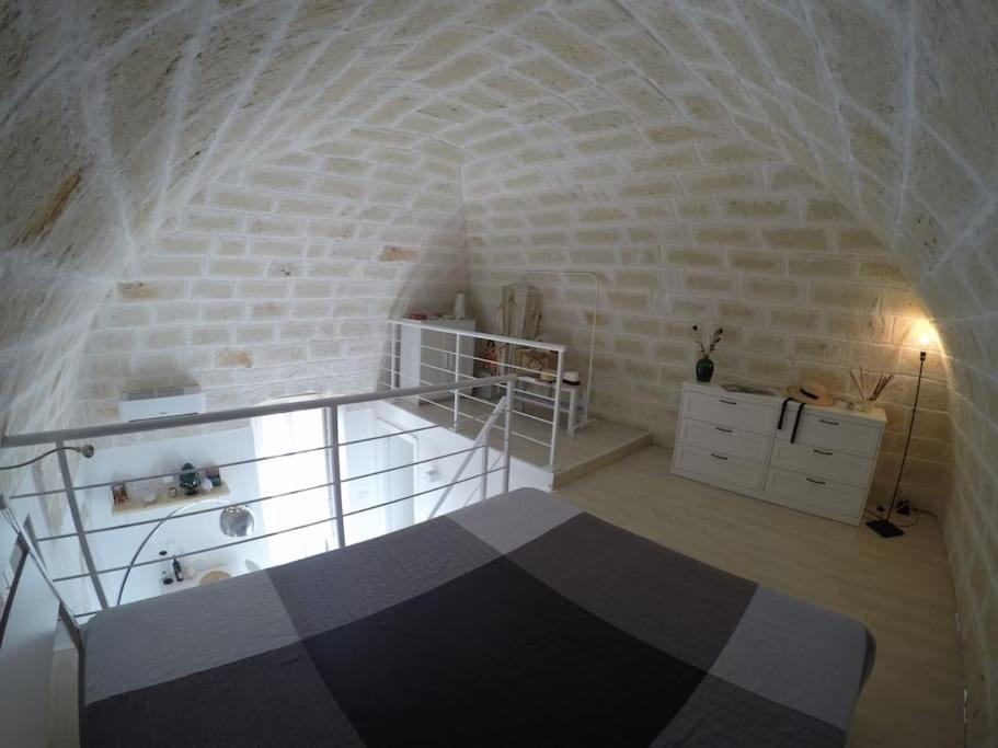 Pokój z łóżkiem i białą ceglaną ścianą w obiekcie La dolce casa - Puglia last minute w mieście Carovigno