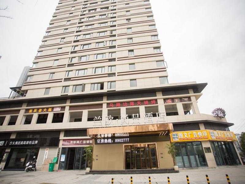 Un alto edificio bianco con un negozio di fronte di LanOu Hotel Tongren Wanshan Jinlin Avenue a Tongren