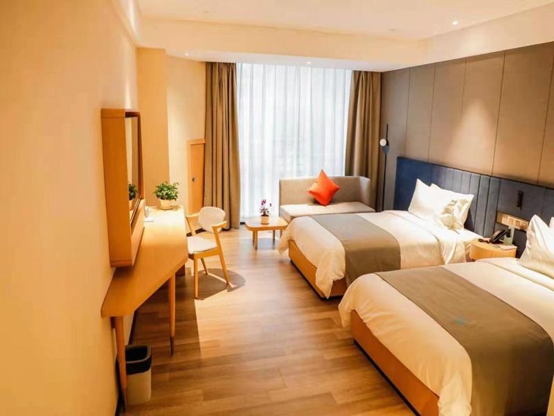 a hotel room with two beds and a desk at LanOu Hotel Jinzhou Red Star Macalline in Jinzhou