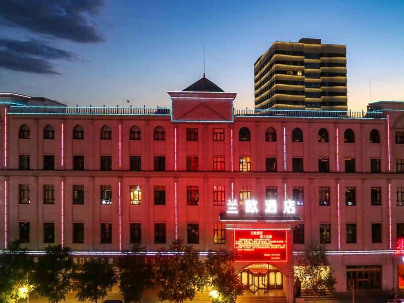 a large pink building with a tower on top of it at LanOu Hotel Zhangye Hexi College Ganquan Park in Zhangye