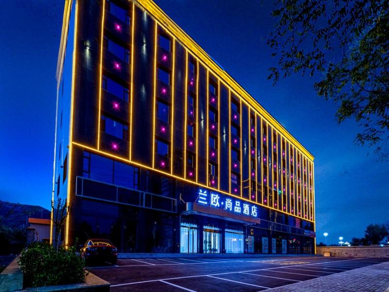 un gran edificio con una fachada iluminada por la noche en LanOu Hotel Yangquan North Railway Station, en Yu