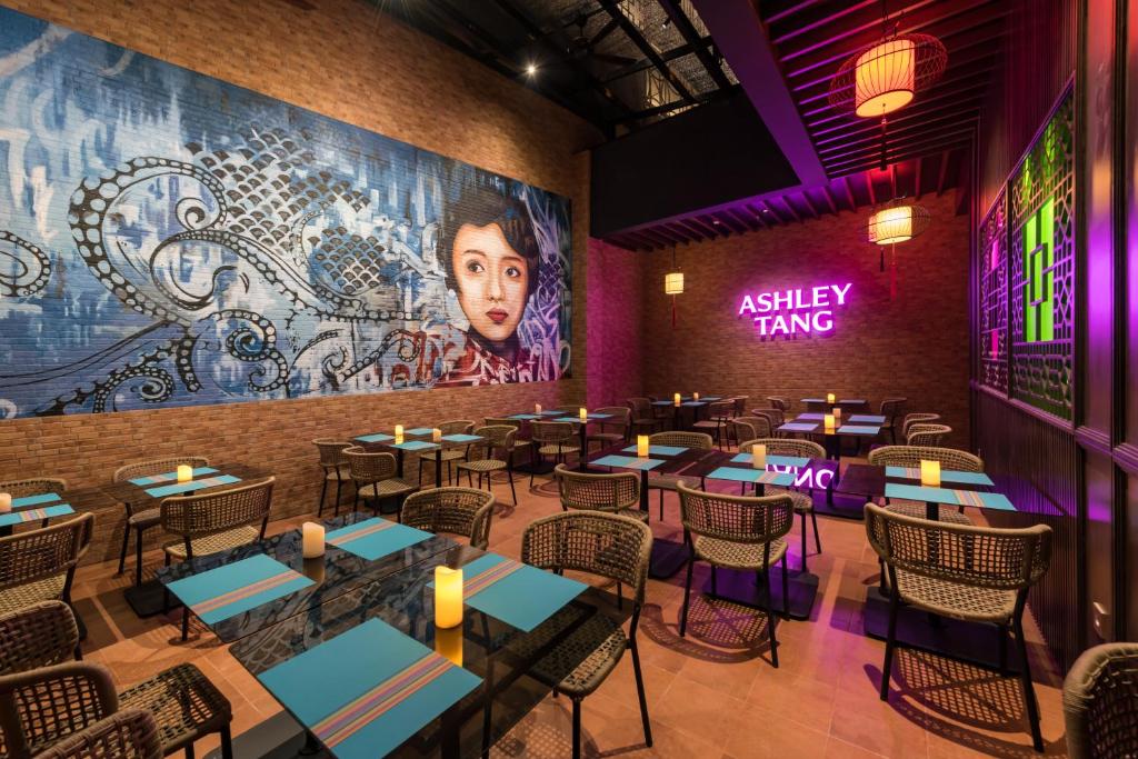 a restaurant with tables and chairs and a large mural at Ashley Tang Menteng Jakarta in Jakarta