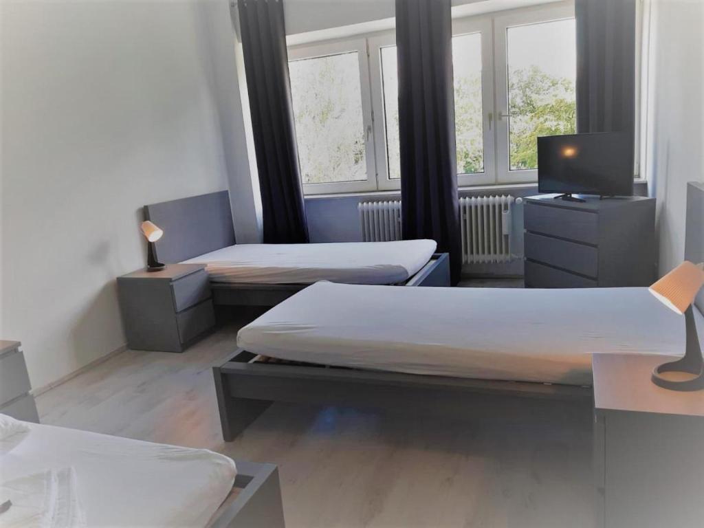 a room with two beds and a tv and windows at Mehrbett-Apartment 7 Citynah, einfache Ausstattung in Hamburg