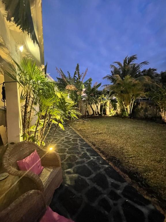 - une vue nocturne sur un jardin avec un bâtiment dans l'établissement Coquette villa privée au bord de l'océan, à Pointe aux Cannoniers
