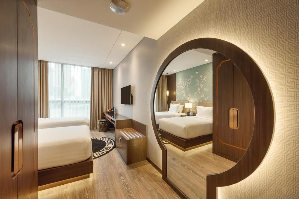 a bedroom with two beds and a mirror at Ashley Tang Menteng Jakarta in Jakarta