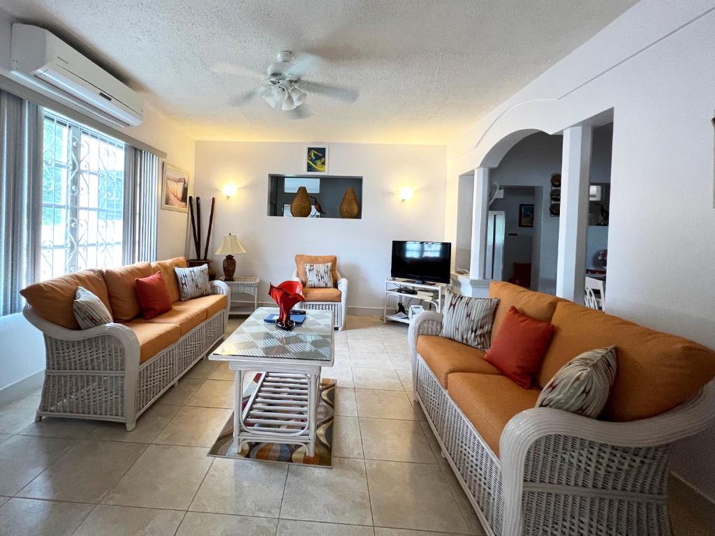 a living room with two couches and a table at Welcome to the unpretentious and breezy Graceville, steps away from the beach in Saint James