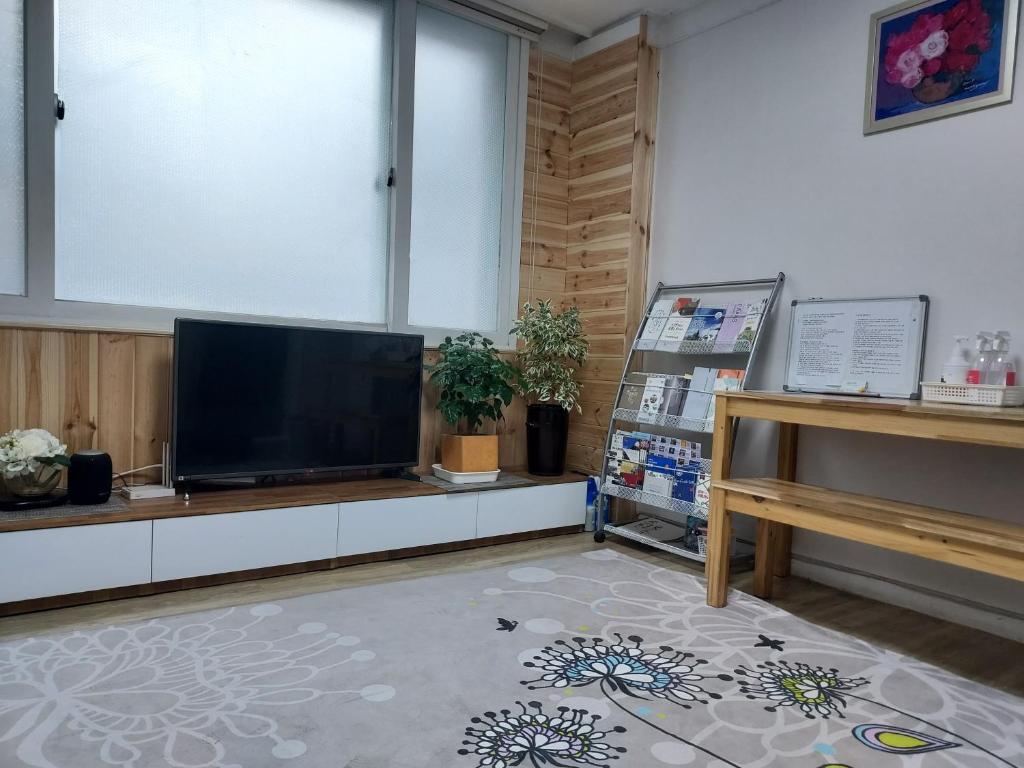 a living room with a flat screen tv and a piano at J&J Guesthouse in Jeonju