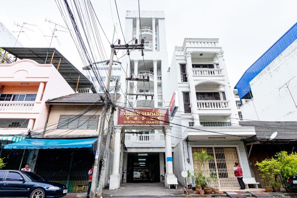 Boonchai Mansion في هات ياي: مبنى على شارع فيه سيارات تقف امامه