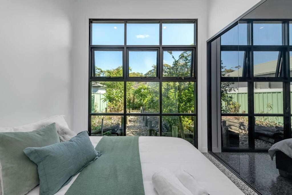 a white bed in a room with large windows at Two Dreamy Properties In One in Culburra Beach