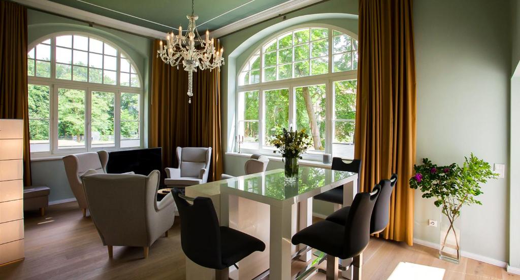 una sala da pranzo con tavolo, sedie e finestre di Parkresidenz Lychen, Ferienwohnung 3 a Lychen