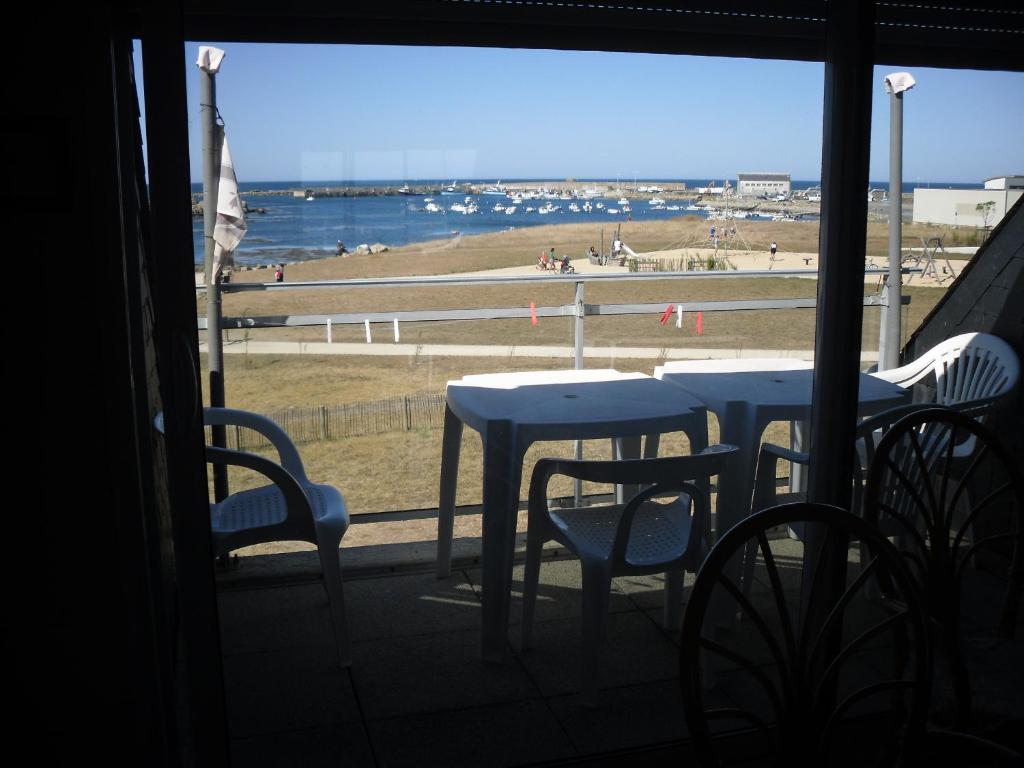 een raam met tafels en stoelen met uitzicht op het strand bij Océan in Penmarcʼh