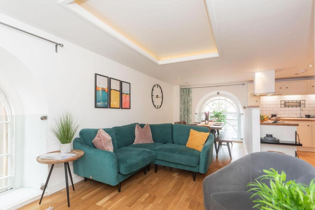 ein Wohnzimmer mit einem grünen Sofa und einer Küche in der Unterkunft Panda Sanctuaries, Kensington Chapel Apartment in Bath