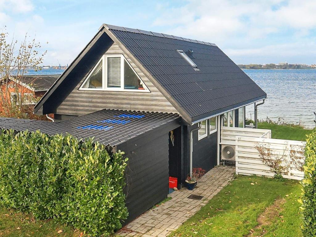 a small house next to a body of water at 4 person holiday home in Middelfart in Middelfart