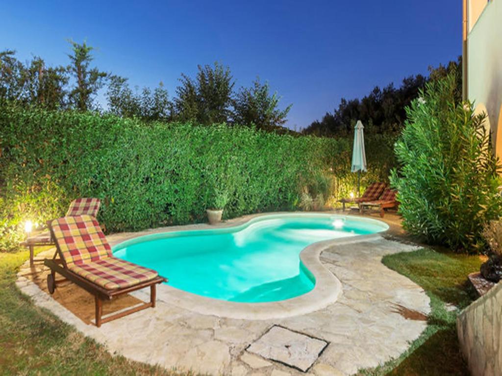 una piscina con una silla y una silla en Amazing apartment Green Paradise with pool and whirpool near the beach en Vinkuran