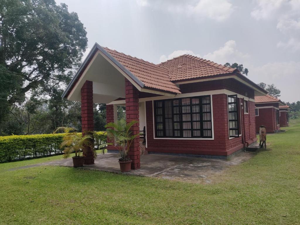 a small red house with a grass yard at Dubare Inn in Madikeri