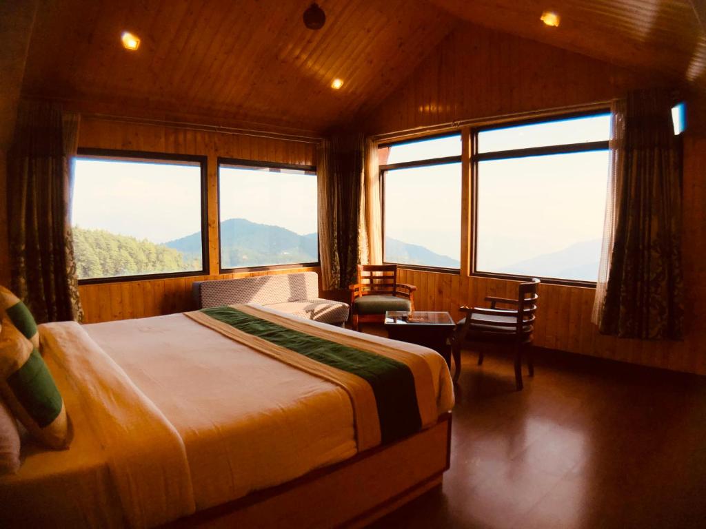 een slaapkamer met een groot bed en grote ramen bij The Himalayan Escape in Mundaghat 