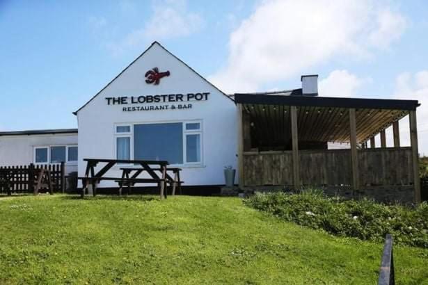 a building with a picnic table in front of it at The Lobster Pot Cottage Church Bay in Llanrhyddlad