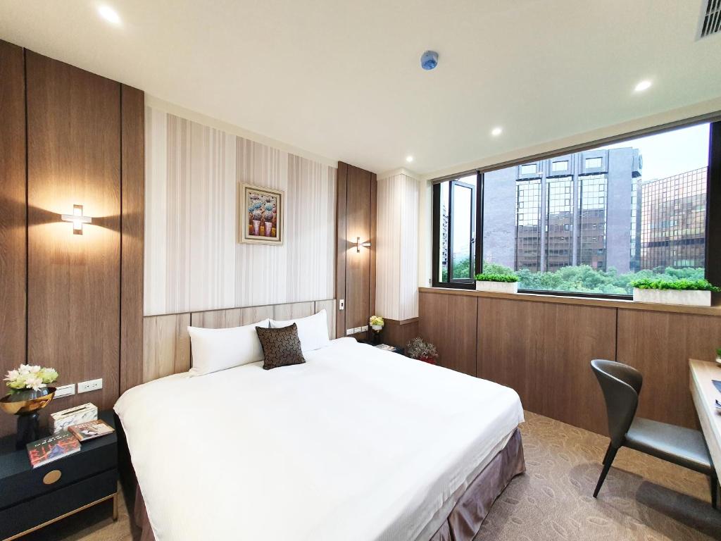 um quarto com uma cama branca e uma grande janela em Grace Hotel Dunbei em Taipei