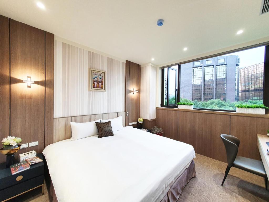 a bedroom with a white bed and a large window at Grace Hotel Dunbei in Taipei