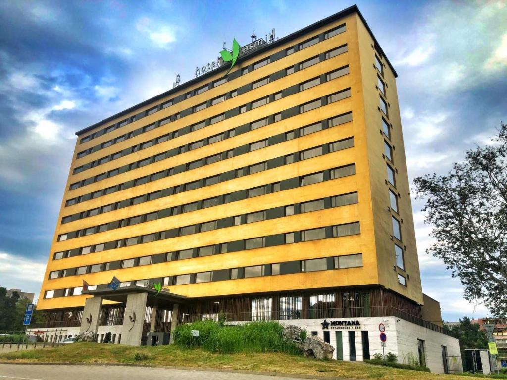 a tall yellow building with a green sign on top at Hotel Yasmin Košice in Košice