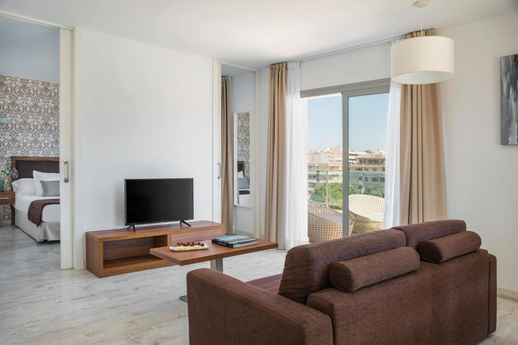 a living room with a couch and a television at Porto Drach Aparthotel & Suites in Porto Cristo