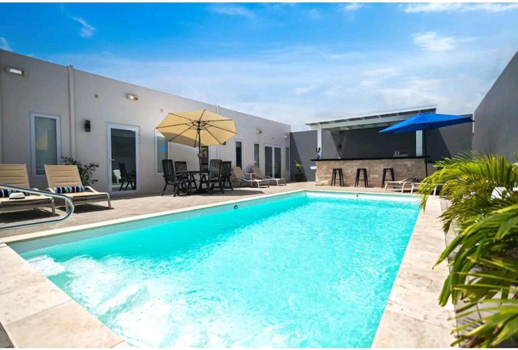 a large swimming pool with a patio and umbrella at Bida Marino Residence Aruba in Palm-Eagle Beach