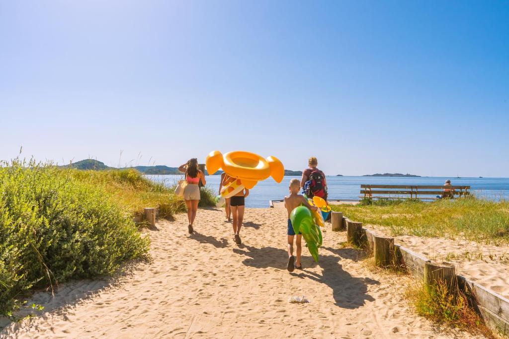 um grupo de pessoas caminhando por uma praia de areia em Topcamp Sjøsanden - Mandal em Mandal