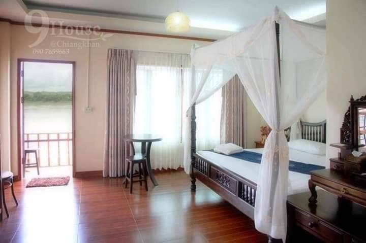 um quarto com uma cama de dossel, uma mesa e uma janela em 9 เฮ้าส์ เชียงคาน em Chiang Khan