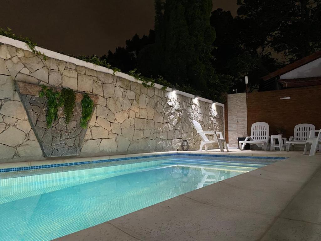 una piscina con sillas y una pared de piedra en El Horreo Apart, en Villa Gesell