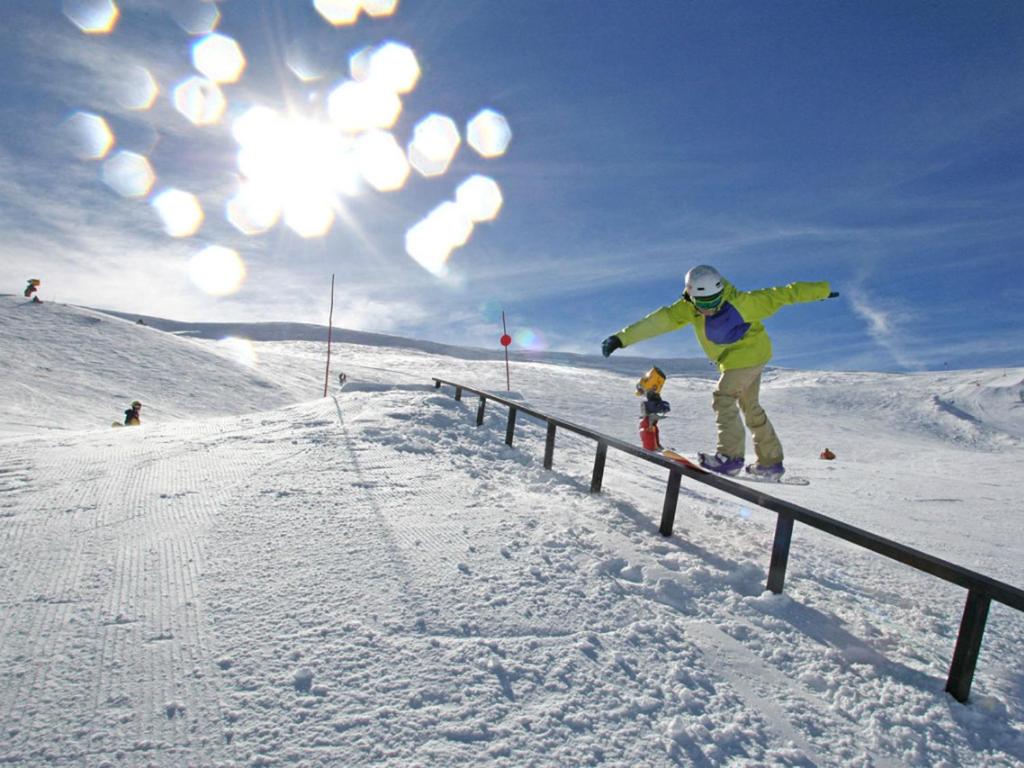 a person riding a snowboard on a rail in the snow at Apartamentos Sierra Nevada 3000 in Sierra Nevada