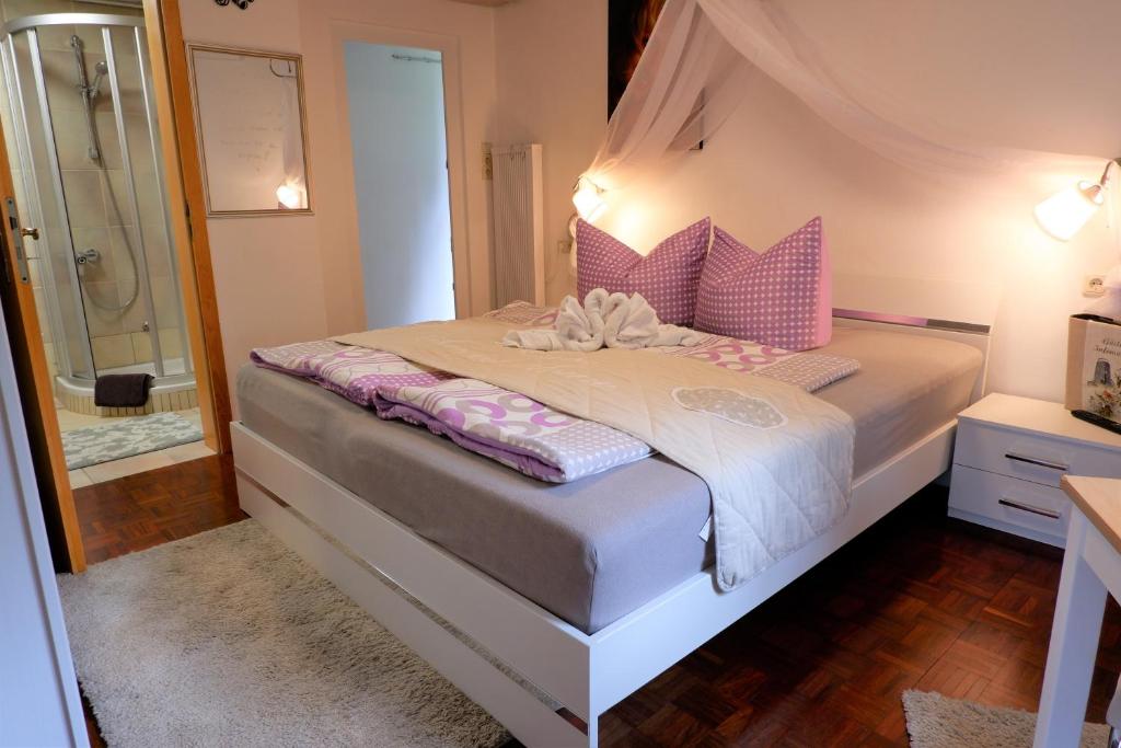 a bedroom with a bed with pink pillows and a shower at Frühstückspension Mayer-Schiller in Bernried