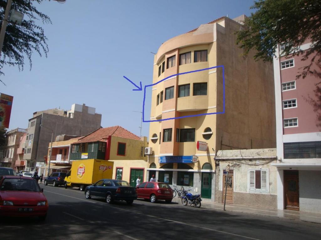un edificio alto in una strada di città con auto parcheggiate di Avenue Baltazar Lopes da Silva 45 a Mindelo