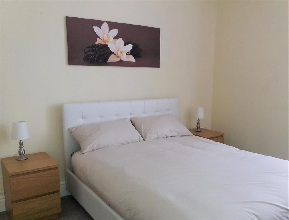 a bedroom with a white bed and two night stands at Home from Home near LFC, EFC & train station in Liverpool