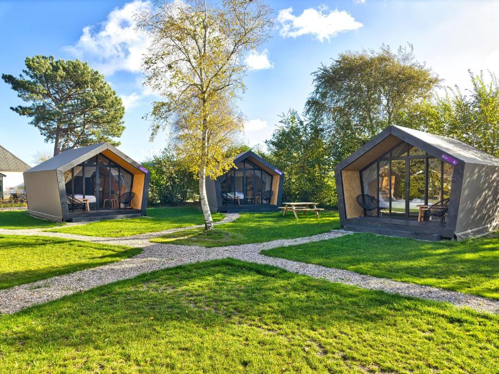 twee cottages in het gras met een boom bij Tenthuisje in het groen, een suite met eigen badkamer in Callantsoog
