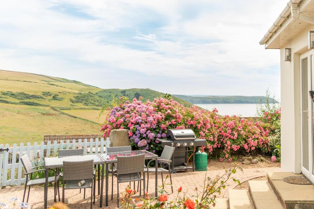 a patio with a bbq grill and flowers at Lower Upover in Woolacombe