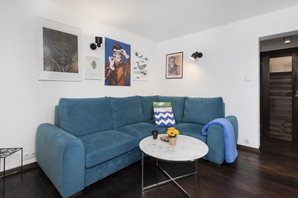 a blue couch in a living room with a table at Warsaw Cosy&Sunny Apartment Górnośląska by Renters in Warsaw
