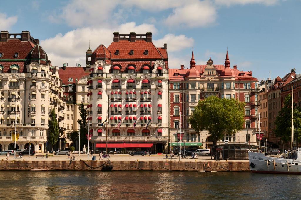 a large building with a red roof next to a river at Hotel Diplomat Stockholm in Stockholm
