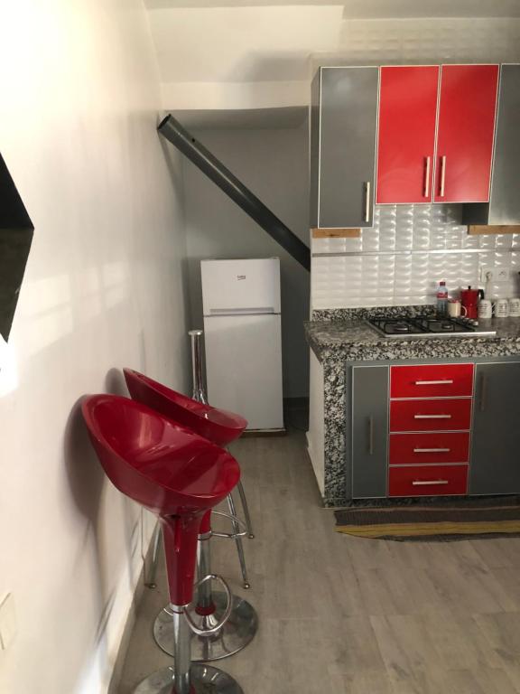 a red stool in a kitchen with red cabinets at Studio luxury ALKHAYMA in Khemisset
