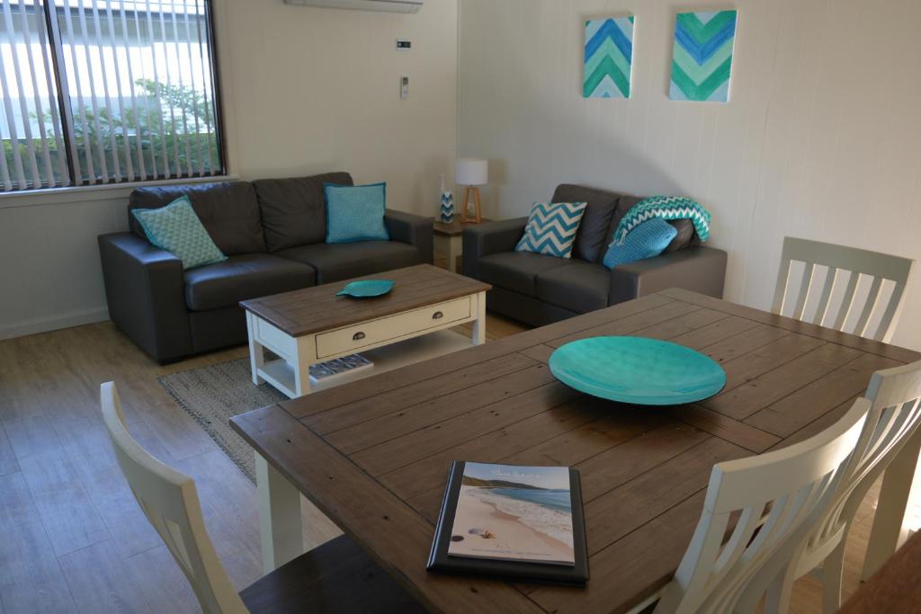 sala de estar con mesa y sofá en Baltica Beach House, en Culburra Beach