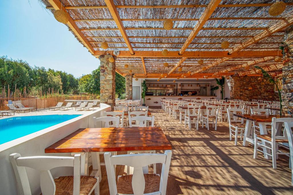 a patio with tables and chairs next to a pool at Coralli Seaside Resort in Livadakia