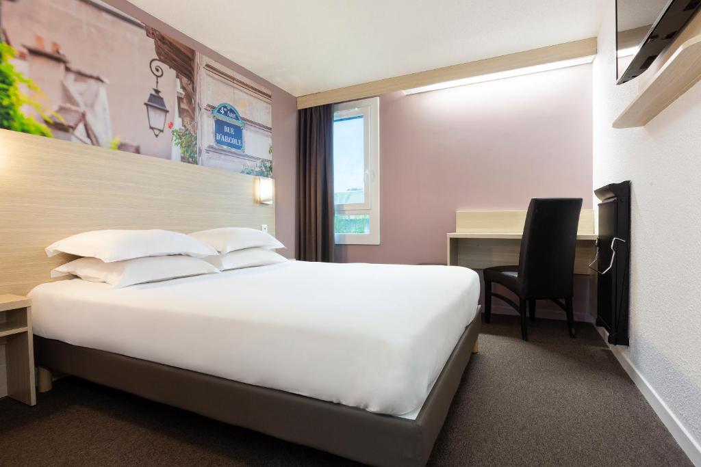 シェルにあるB&B HOTEL Marne-la-Vallée Chellesの大きなベッドとデスクが備わるホテルルームです。